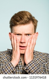 Uncomprehending Puzzled Perplexed Confused Man Grasping His Face In Disbelief. Portrait Of A Young Guy On Light Background. Emotion Facial Expression. Feelings And People Reaction.