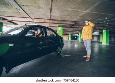 Unconfident Young Woman Parking Car On Empty Spot In Underground Parking With Man Help