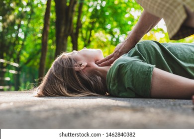 Unconscious fainted girl having pulse checked by an old woman – Teenager lying on the ground while her pulse is verified by an elder citizen on teen’s carotid artery - Shutterstock ID 1462840382