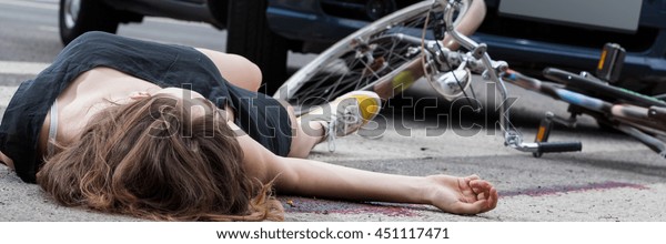 Unconscious female cyclist lying on street after\
road accident