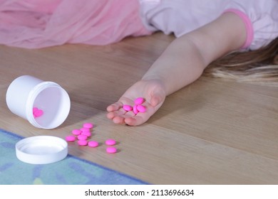 Unconscious little child (girl) with pink pills laying on the floor at home. Danger of medicament intoxication.