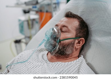 Unconscious patient with oxygen mask on hospital bed. Man in intensive care unit in hospital. - Powered by Shutterstock