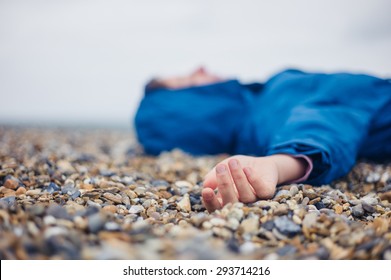 An Unconscious Woman Is Lying On A Shingle Beach