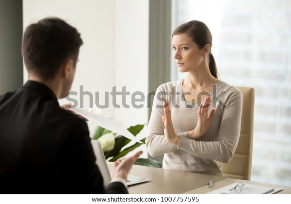 Unconvinced in honesty of business agreement
female entrepreneur refusing to sign contact with businessman.
Skeptical young woman rejecting job offer when sitting at desk in
front of hiring
manager