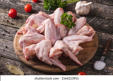 Uncooked chicken wings  on a wooden cutting board with spices. Closeup