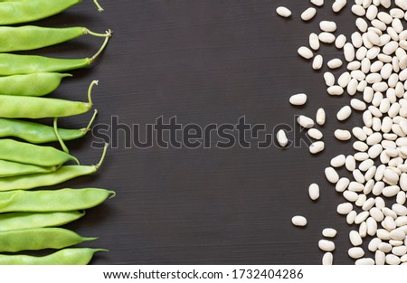 Uncooked dried white haricot beans with fresh raw green beans pod plant on rustic table. Heap of legume haricot bean background ( Phaseolus vulgaris )