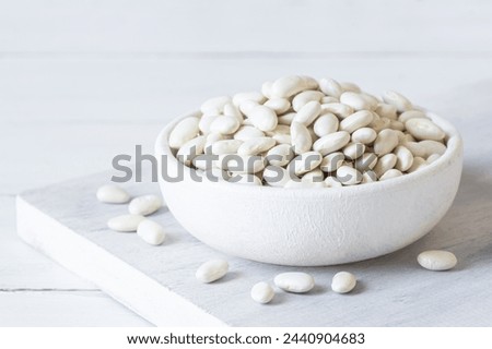 Uncooked dried white haricot beans in bowl or spoon on table. Heap of legume haricot bean background ( Phaseolus vulgaris )
