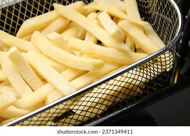 Uncooked french fries in metal basket, closeup