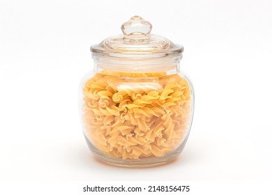 Uncooked Fusilli Pasta in Glass Jar on White Background. Raw and Dry Macaroni. Unhealthy and Fat Food. Italian Culture