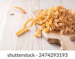 Uncooked Fusilli Pasta Scattered on Wooden Board