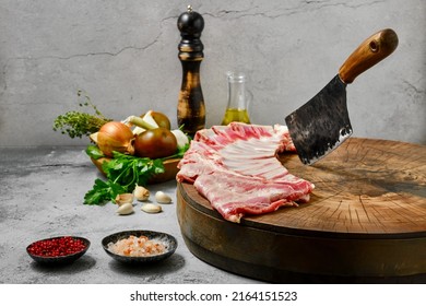 Uncooked lamb flap ribs with ingredients on wooden log