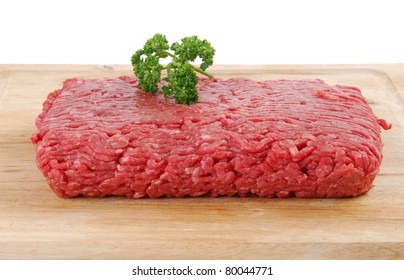 Uncooked lean ground beef on a cutting board with parsley garnish