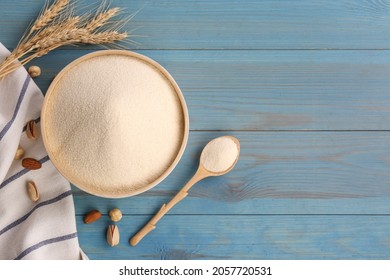 Uncooked organic semolina, spikelets and nuts on light blue wooden table, flat lay. Space for text