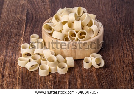 uncooked pasta calamarata in bowl on wooden background