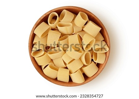 Uncooked pasta calamarata in wooden bowl on white background