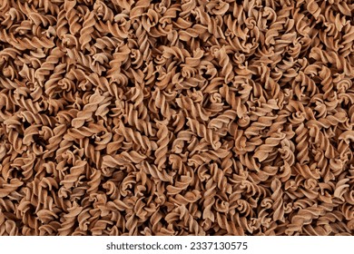 Uncooked Pasta di Lino, close-up. Flaxseed gluten free pasta is rich in fiber, iron, B vitamins and Omega-3. Fusilli made from flax and corn flour. Low glycemic index food.