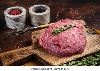 Uncooked Raw beef veal cheeks on wooden board. Dark background. Top view.