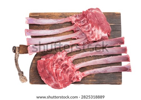 Uncooked raw lamb rack bone ribs in meat arranged on wooden cutting board isolated on white background culinary ingredient.