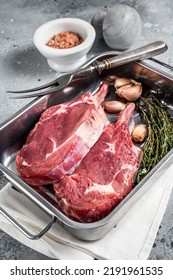 Uncooked Raw Tomahawk Veal Steaks In Steel Tray With Herbs. Gray Background. Top View.