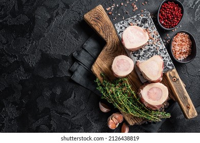 Uncooked Raw veal Marrow bones on butcher board with meat cleaver. Black background. Top view. Copy space - Powered by Shutterstock