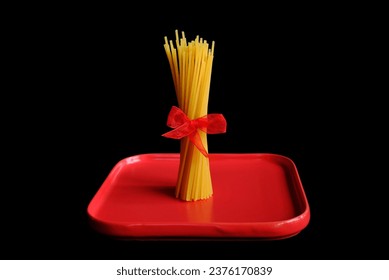 Uncooked spaghetti tied with red ribbon - Powered by Shutterstock