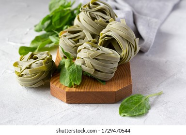 Uncooked Spinach Pasta Tagliatelle (agli Spinaci) With Fresh Spinach Leaves On Wooden Board