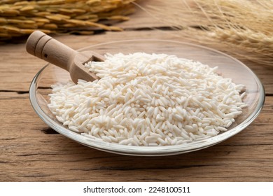 uncooked Thai sticky rice in glass plate on wooden table - Shutterstock ID 2248100511