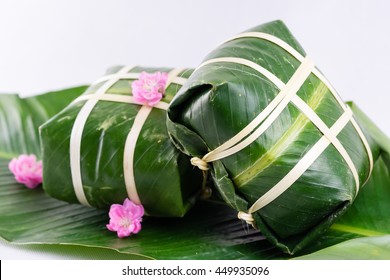 Uncooked Vietnamese Chung Cake isolated on white. It's a square glutinous sticky rice cake, stuffed with pork meat, green beans and wrapped in bamboo leaf. Traditional Vietnamese New Year (Tet) food.