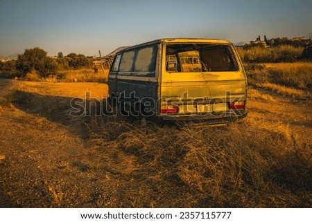 Uncover the poignant tale of abandonment as the golden hour illuminates a forsaken green Volkswagen Transporter, nestled among the grasses on the roadside of Crete, a time-tinged memory frozen in time
