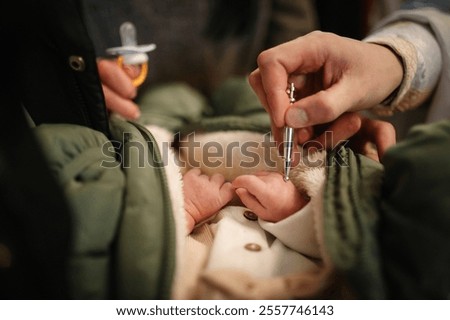 Unction at baptism. Anointing. The priest performs chrism at baptism. Temple, Orthodoxy. Closeup of tiny baby hands, sacrament of baptism ceremony.