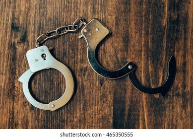 Uncuffed, Open Hand Cuffs On Wooden Police Office Desk, Top View