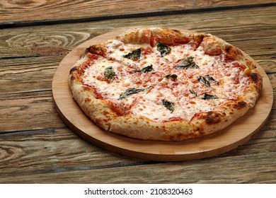 Uncut Italian Pizza Served With Fresh Basil Leaf On Wooden Board On Dark Texture Background. Hot Pizza With Tomatoes And Pesto Sauce