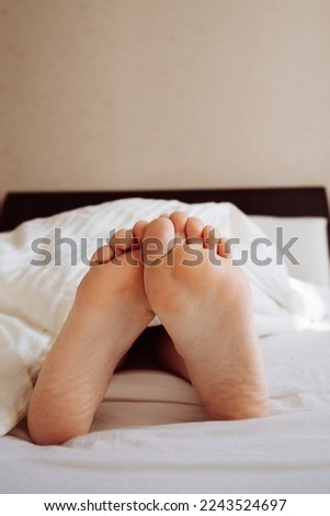 Under the blankets, the woman's legs stick out