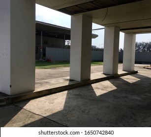 Under the building with columns and shadows.
