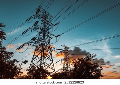 Under a clear sky, the setting sun casts a warm glow over the mountain peak. The silhouette of a towering steel transmission tower stands tall against the fading light, creating a striking contrast. - Powered by Shutterstock