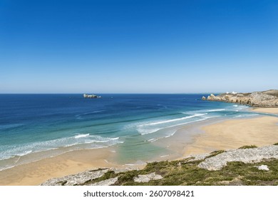 Under a cloudless sky, waves roll in fine parallel lines on Pen Hat beach. The panorama offers a stunning view of the Iroise Sea and its vibrant shades.