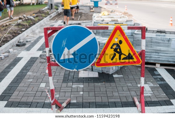 Under construction sign closeup.\
Road works sign for construction works in city street on a sidewalk\
road. Repairing. Red, black and yellow triangle road sign\
work.