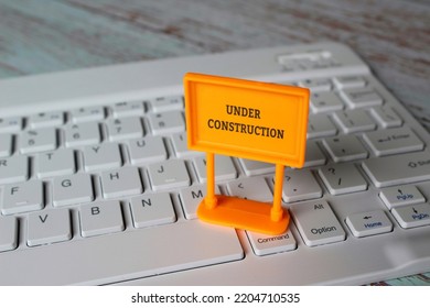 Under construction sign on top of computer keyboard. Computer system under construction, maintenance, repair concept. - Shutterstock ID 2204710535