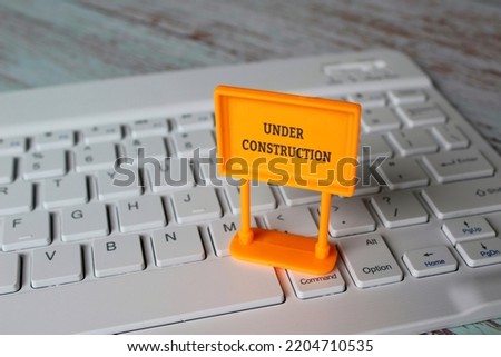 Under construction sign on top of computer keyboard. Computer system under construction, maintenance, repair concept.