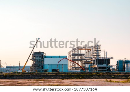 Under Construction site of modern factory. Industry factory buidling with modern warehouse in sunset sky clouds background. 
