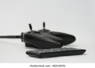 Under control. Black controller and remote on a white background.