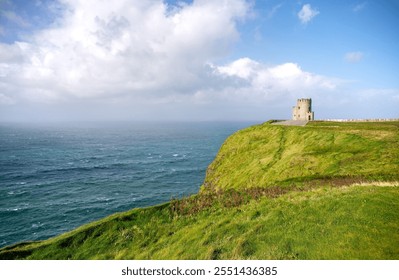 Under a dramatic cloudscape, O’Briens Tower, the stone building at the Cliffs of Moher, looks out over the wind-blown waves of the Atlantic Ocean on a sunny, summer day in County Clare, Ireland.