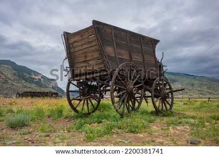 Under overcast skies of Cody, Wyoming lies the remnants of an old town from the days of the Wild West. A stagecoach rests in an open field. 
