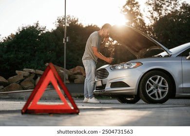 Under the sunlight, red sign, accident, broken automobile, repair. Man is with his car outdoors. - Powered by Shutterstock