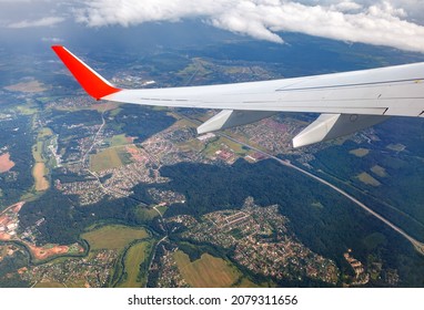 Under the wing of the plane forests, fields and houses. View from the airplane window
