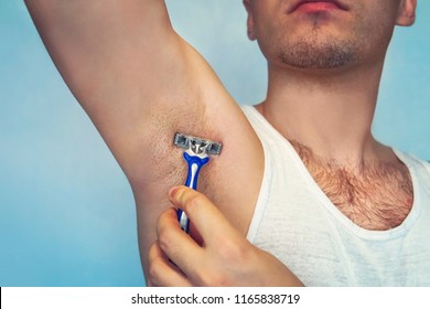 underarm hair removal. Male depilation. Young attractive muscular man using razor to remove hair from his body. the self-care concept. epilation