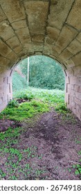 an underbridge arch bricks structure with grassy muddy land with woods as background, half mystery half peaceful nature, Portugal hidden spot, October 2022
