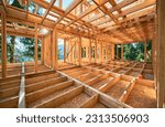 Under-construction residential wooden frame home located near a forest. Commencement of a new construction project for a cozy house or a mountain cottage. Idea of contemporary ecological construction.