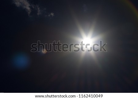 An underexposed shot of the sun at noon - sunbeams and flairs