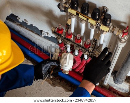 Underfloor heating installation. Water floor heating system interior. Plumbing pipes in apartment during under renovation. Underfloor heating manifold. Worker attache the tube to the collector heating